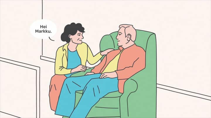 Kuva kohtaamistilanteesta. Mies istuu nojatuolissa. Nainen kyykistyy hänen vierelleen, ottaa katsekontaktin ja asettaa käden miehen olkapäälle.