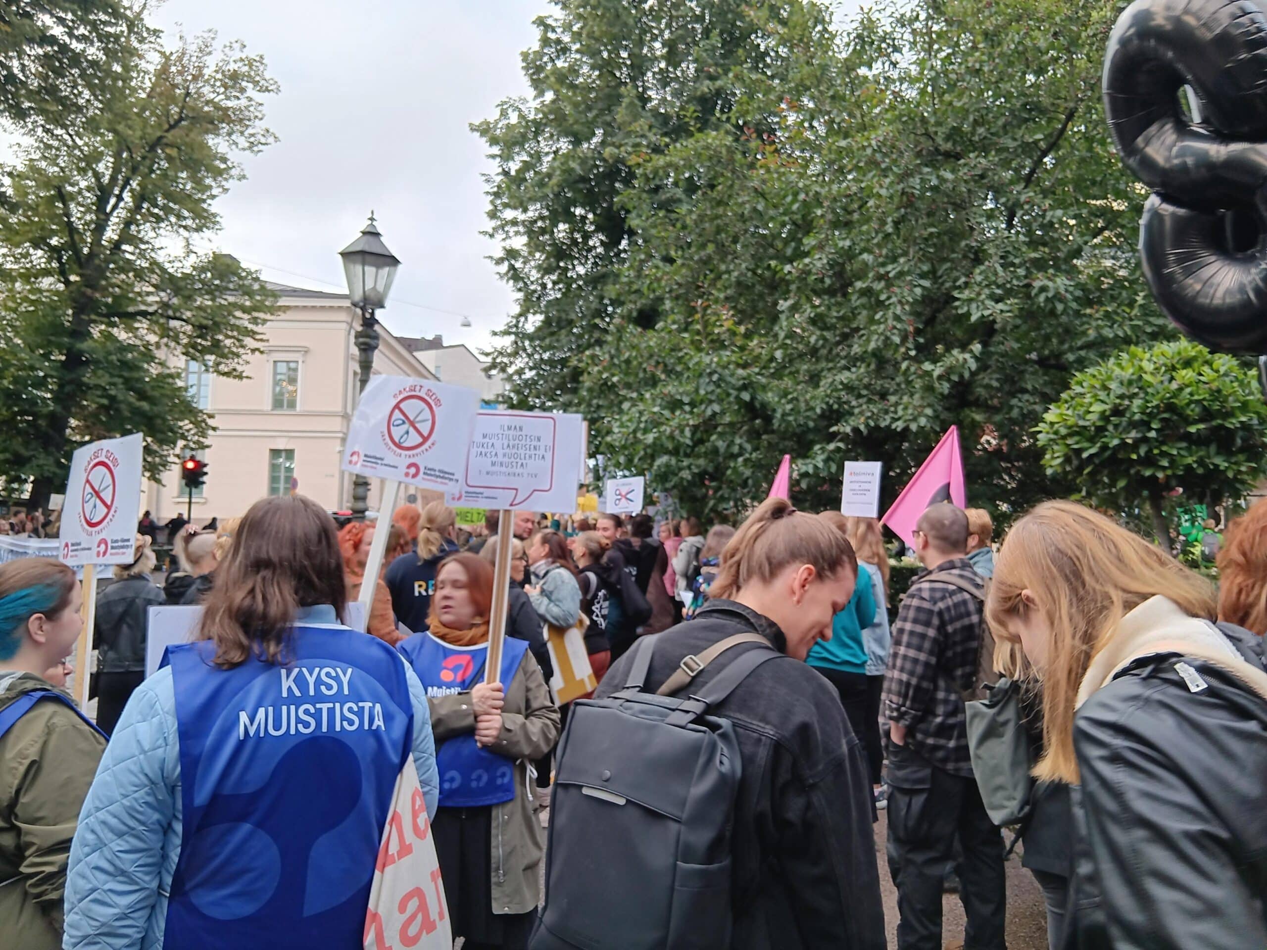 Joukkoa on kokoontunut mielenosoitukseen Esplanadinpuistoon Helsinkiin. Ihmisillä on paljon kylttejä ja banderolleja.