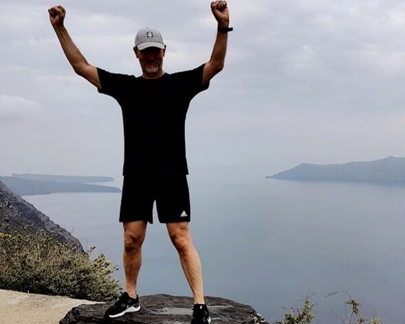 Kuvassa mies seisoo kalliolla kiven päällä ja on nostanut kätensä ylös tuuletukseen. Lippis varjostaa miehen kasvoja niin, ettei niitä erota kunnolla. Taustalla näkyy sumuinen merimaisema.