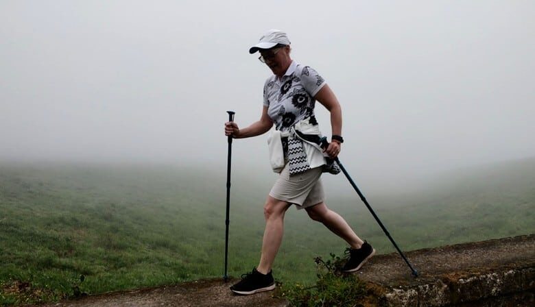 Kuvassa henkilö kävelee sauvakävelyä sumuisessa maisemassa.