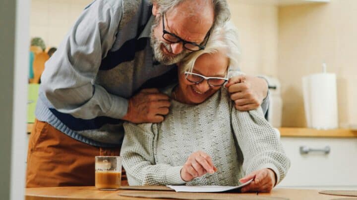 Pariskunta katsoo paperia hymyillen.