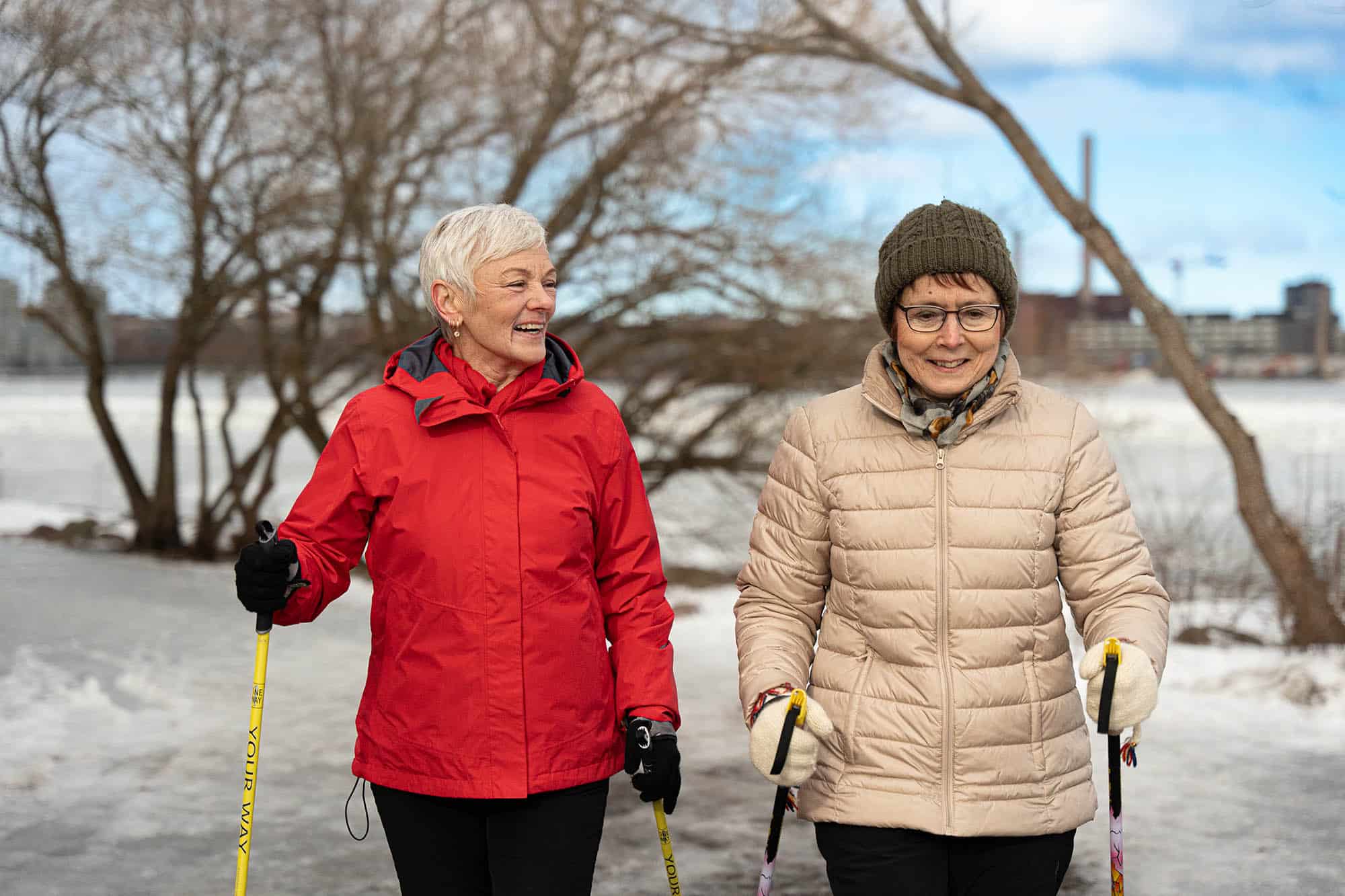 Kaksi naista sauvakävelee talvisessa maisemassa.